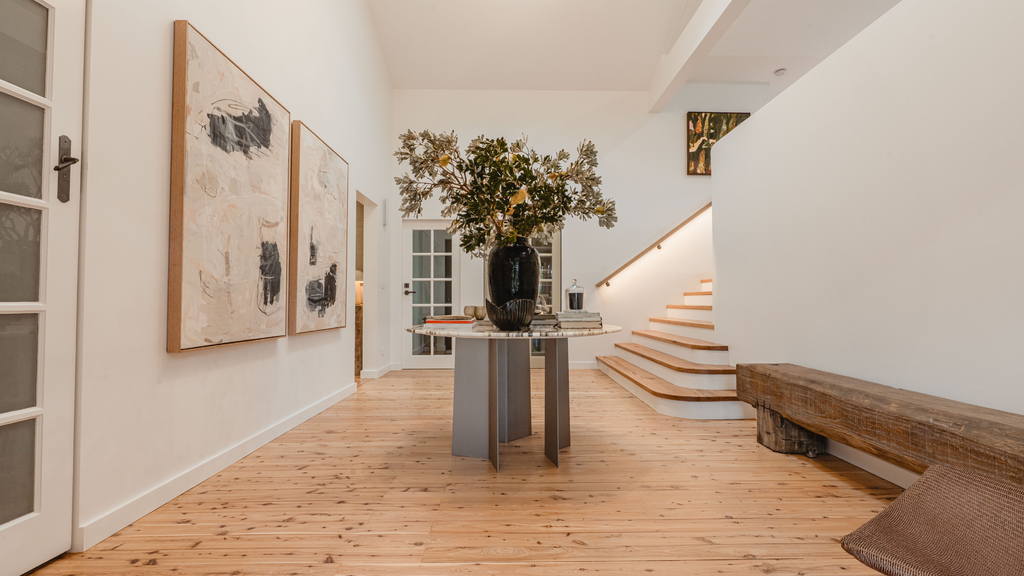 Modern interior with wooden floor, staircase, and wall art