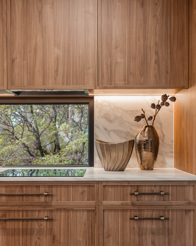 Modern kitchen with wooden cabinets and a window view of trees